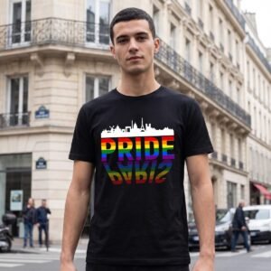 Man on a Paris street wearing a black tee printed with the Paris skyline in white above the word Pride in rainbow capitals and its reflection